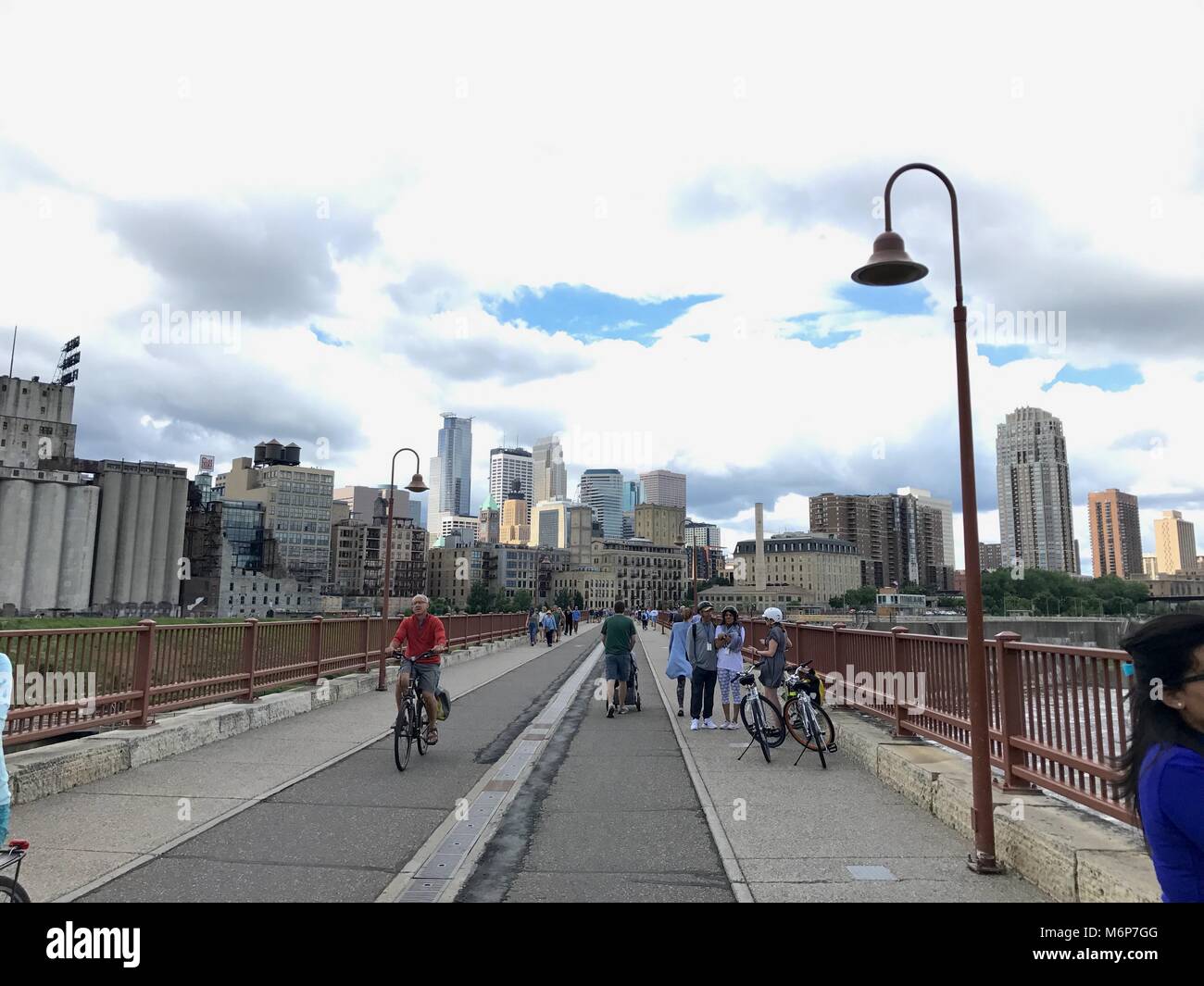 Minneapolis, Minnesota - Circa 2017: People walk and bike on Stone Arch Bridge span Mississippi River against beautiful downtown skyline Stock Photo