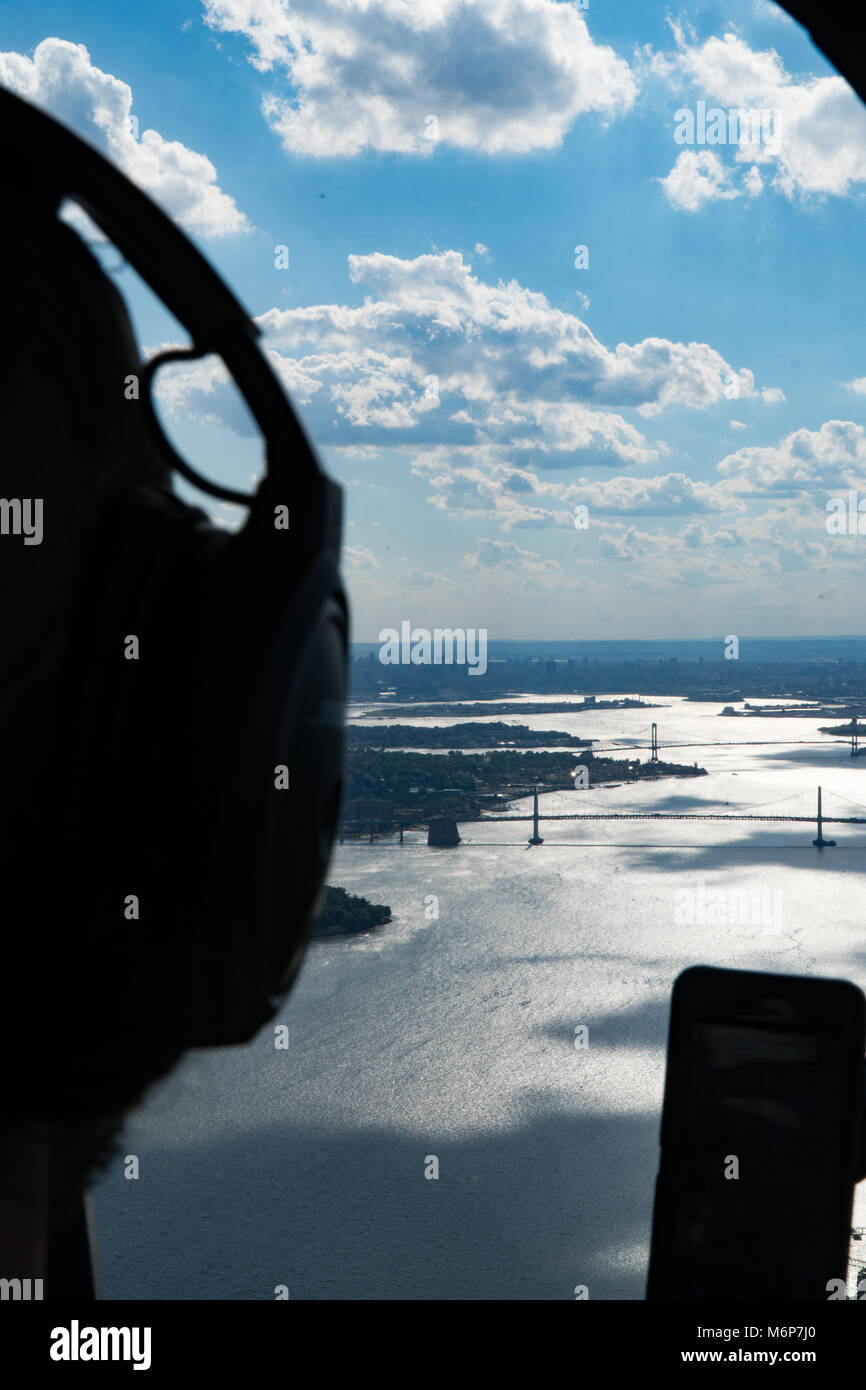 Aerial video of New York City bridges, sun reflection off bay water, bright blue skies. Perspective over shoulder of pilot from inside helicopter Stock Photo