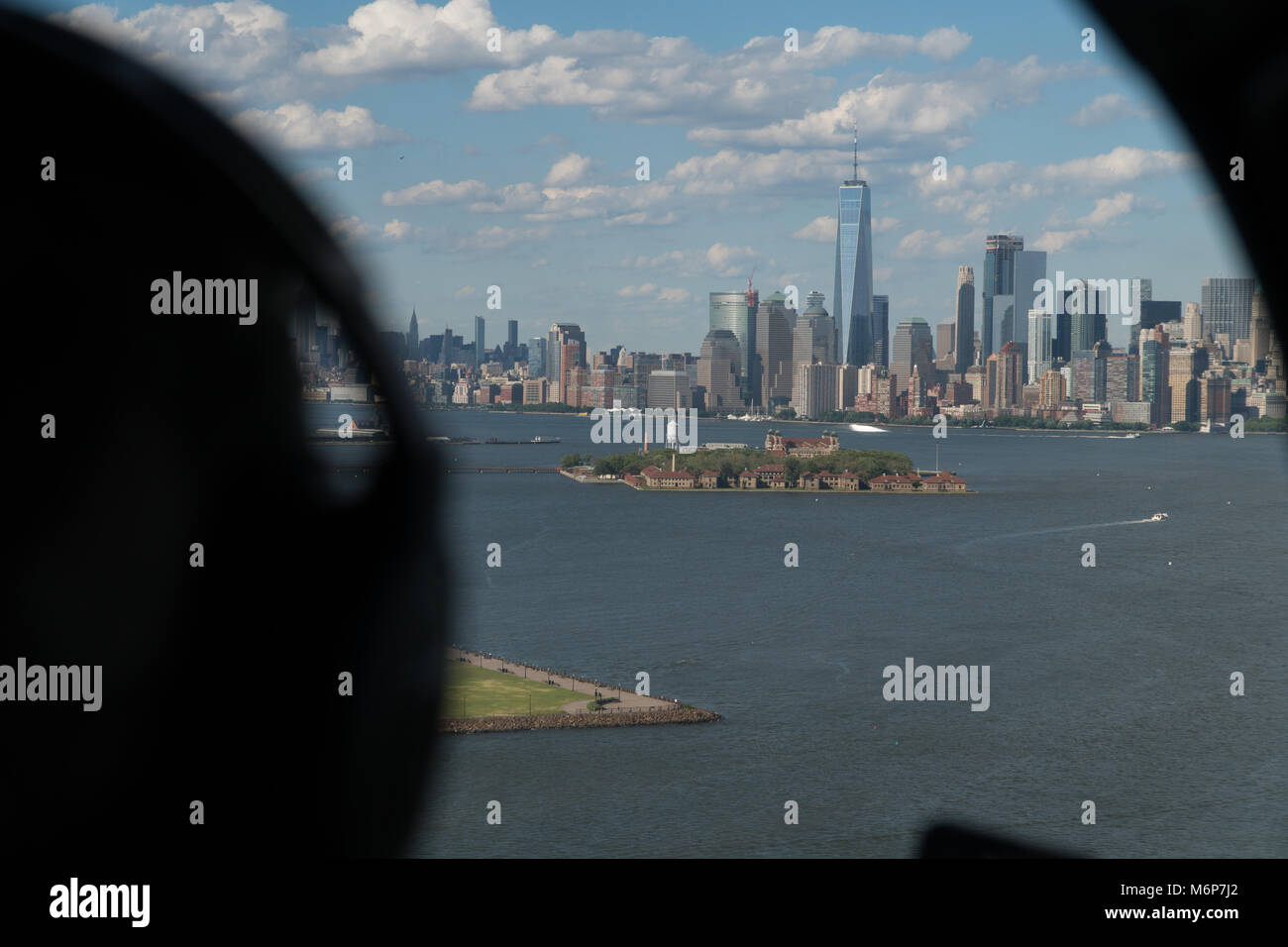 Aerial view over the shoulder of helicopter pilot looking at downtown New York City skyline during the day flying over harbor Stock Photo