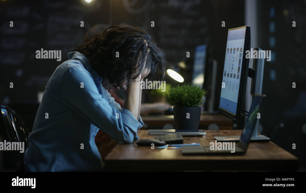 tired overworked female mobile phone app designer holds her head in