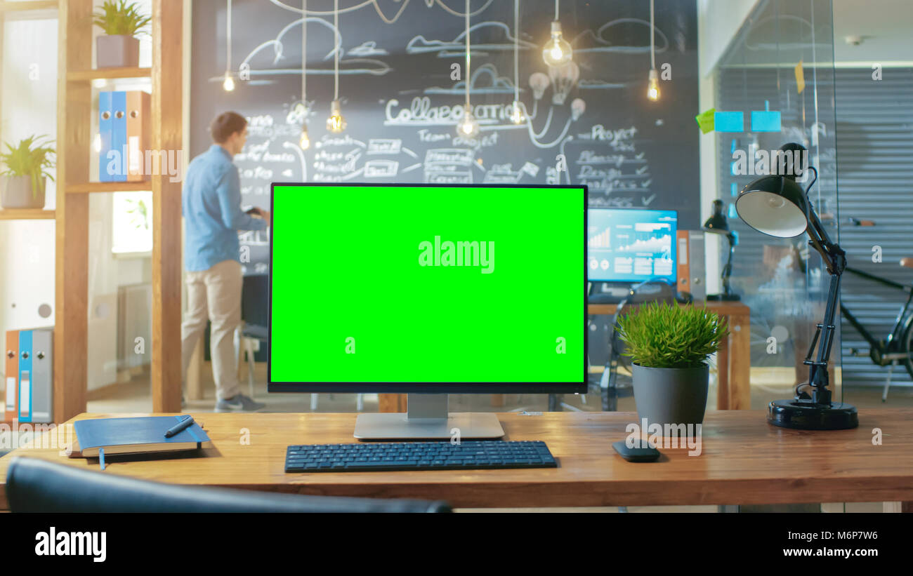 Personal Computer with Mock-up Green Screen Monitor Stands on the Office  Desk, In the Background Man Works in the Creative Office at Daytime Stock  Photo - Alamy