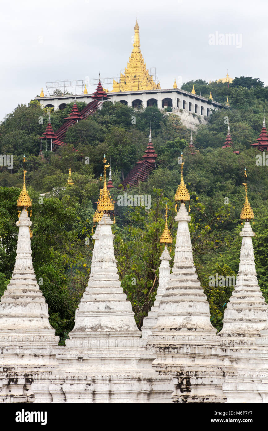 The white stupas of the Sandamuni Pagoda with the Mandalay Hill in the background.. Myanmar (Burma). Stock Photo