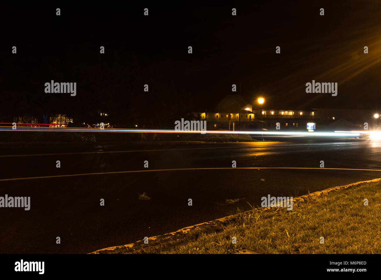 Long exposure light trail of night traffic on a quiet small town main street during a mist rain Stock Photo