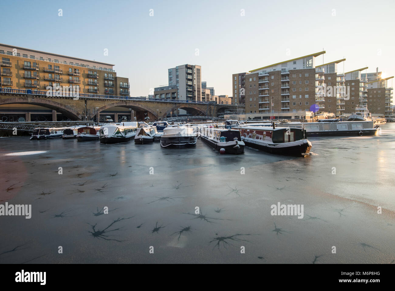 Boats moored in Limehouse Marina, London, where it had snowed and a layer of ice had formed across the water. Stock Photo