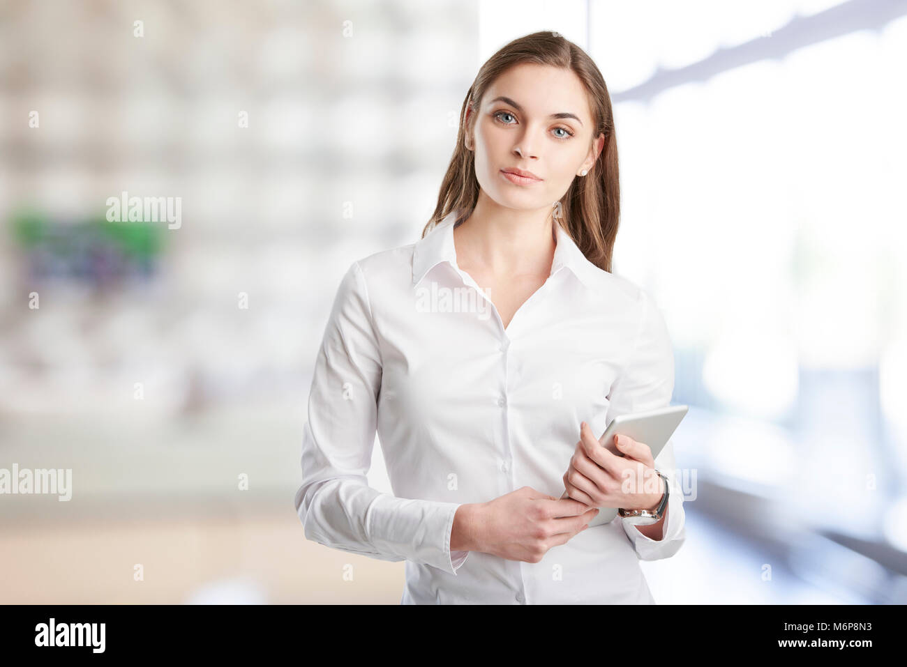 Portrait of young financial assistant businesswoman using digitla tablet while standing at the office. Stock Photo