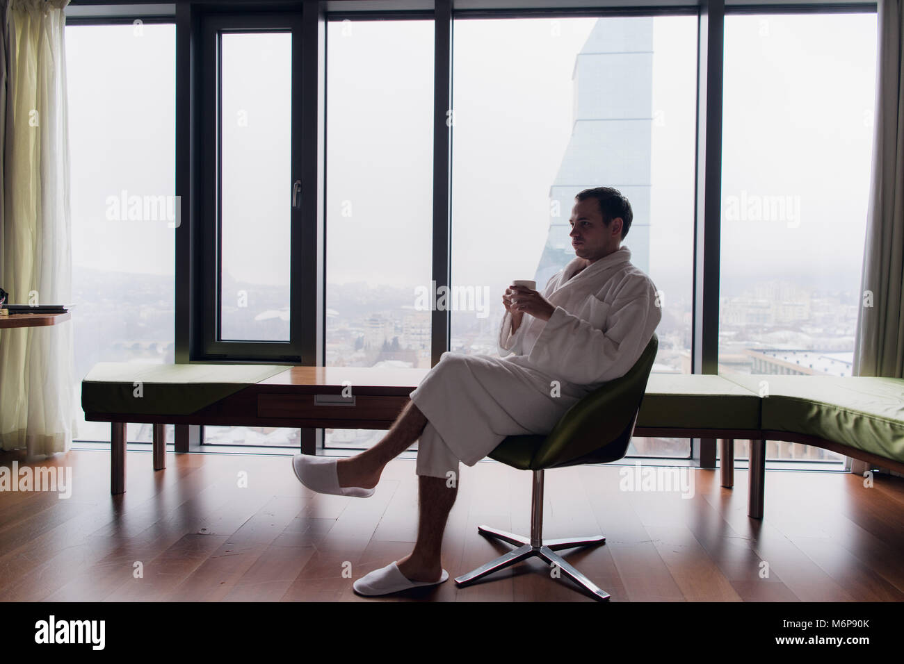 man in bathrobe drinks coffee in luxury hotel in the morning. Stock Photo