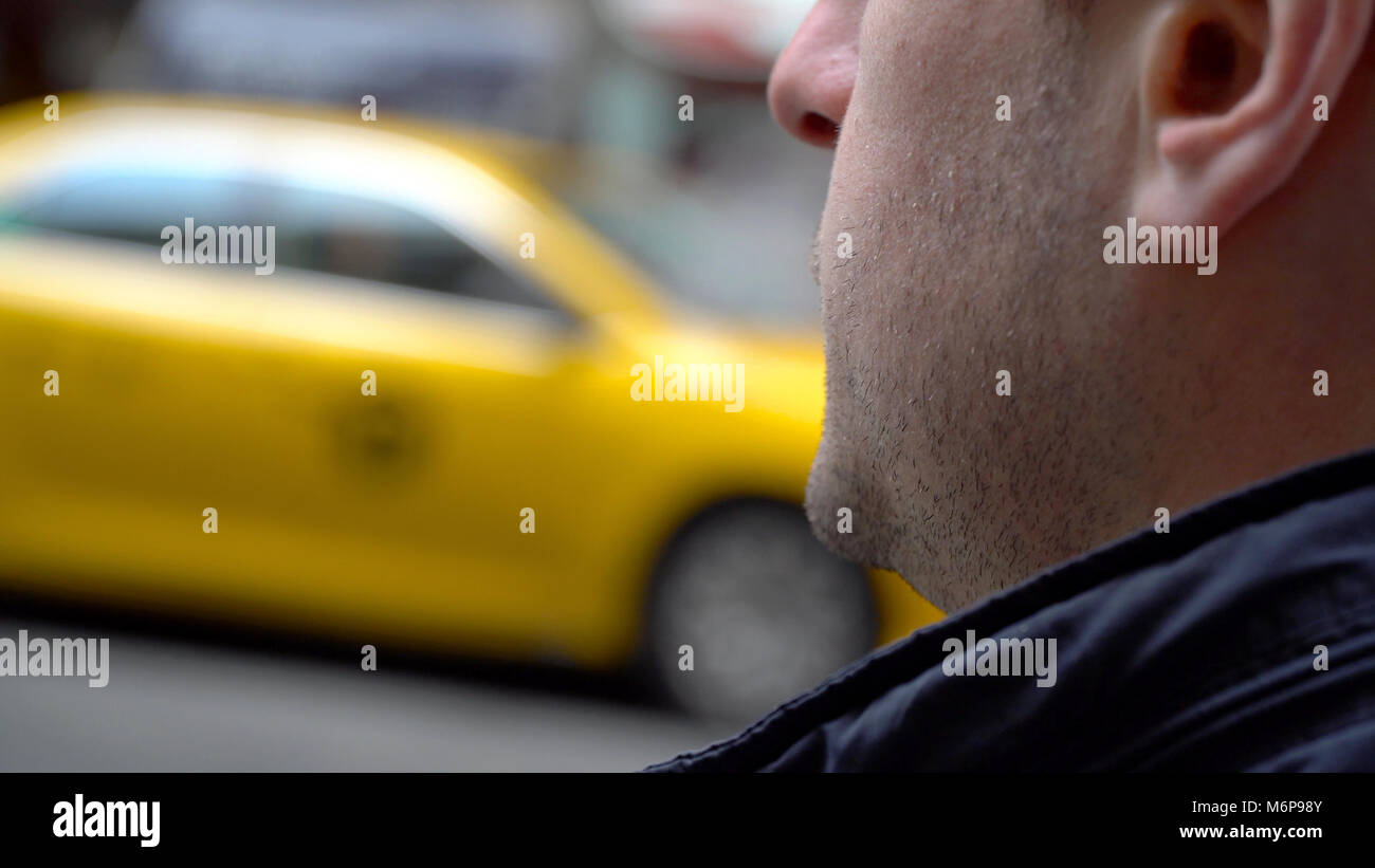 Over shoulder of young man waiting for yellow taxi cab in New York City during day time. Stock Photo