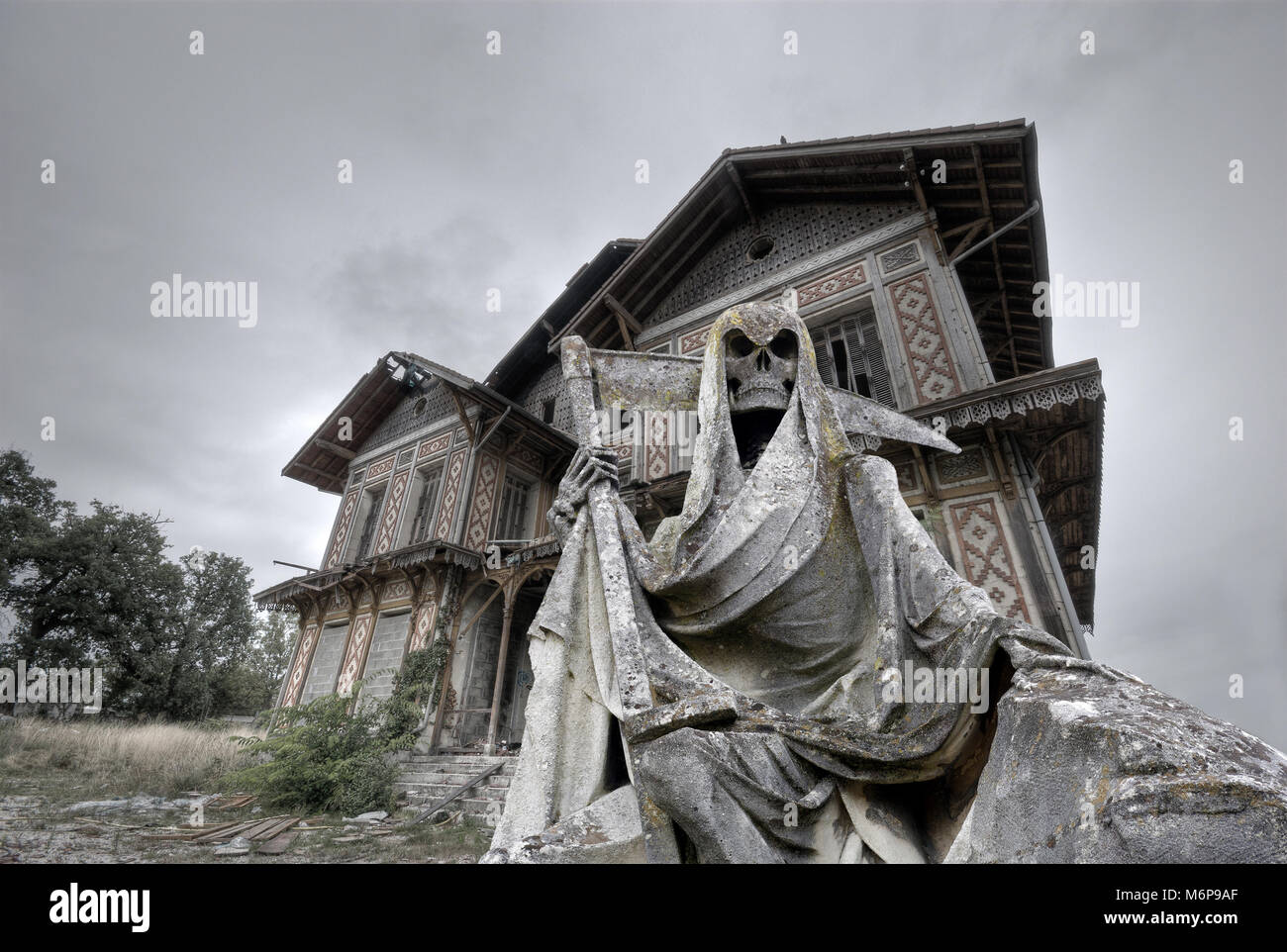 haunted house with a gream reaper statue in foreground Stock Photo