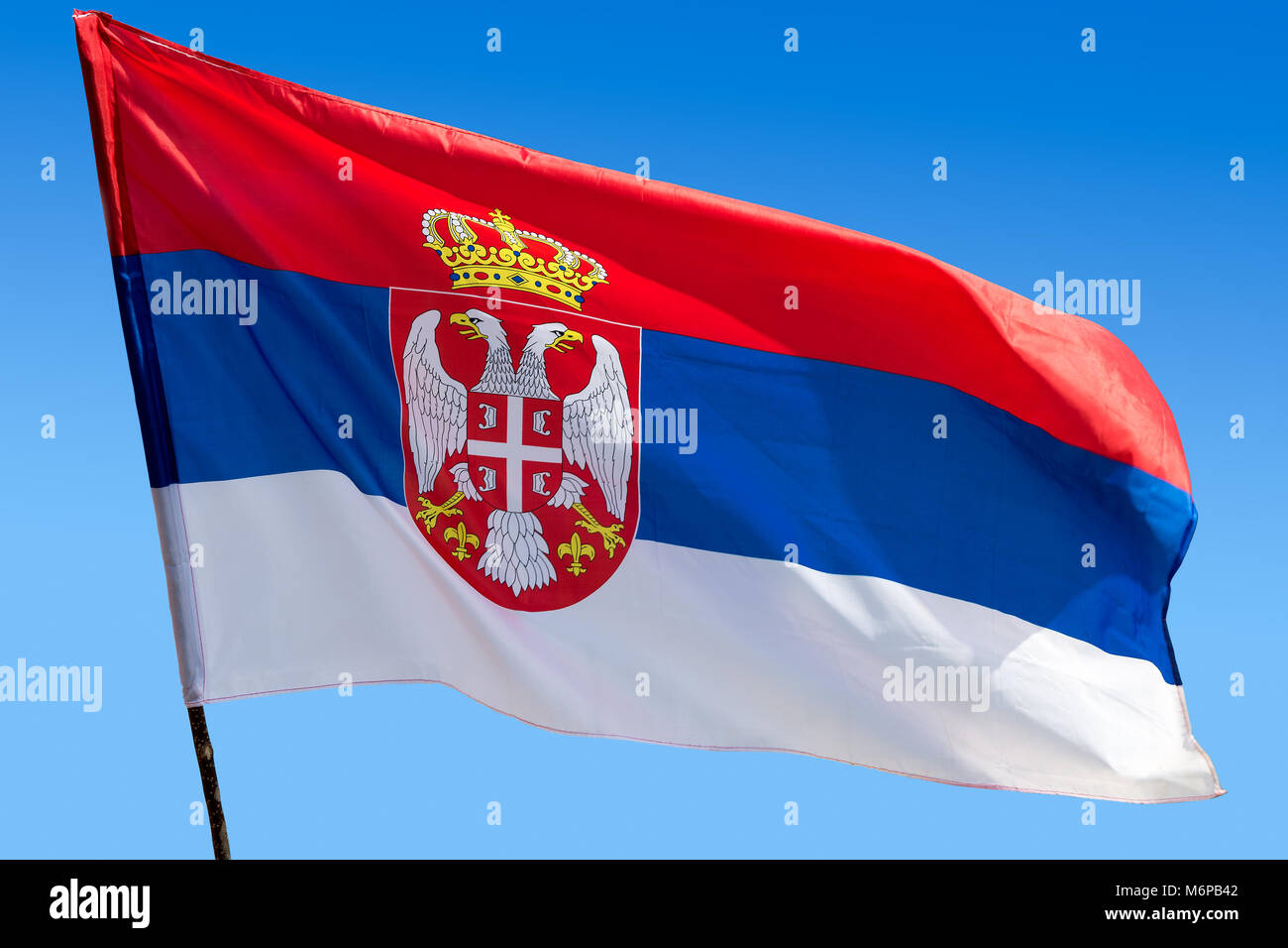 Official flag of republic of Serbia waving against blue cloudless sky Stock Photo