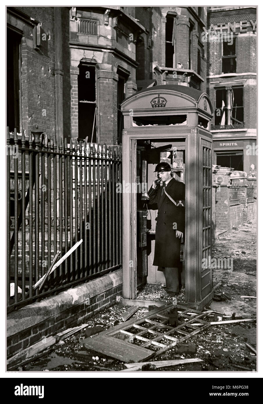 Vintage 1940’s WW2 London Blitz image of bombed out London street with warden still using traditional British telephone box despite the significant damage.... ‘Keep calm and carry on...’ Stock Photo