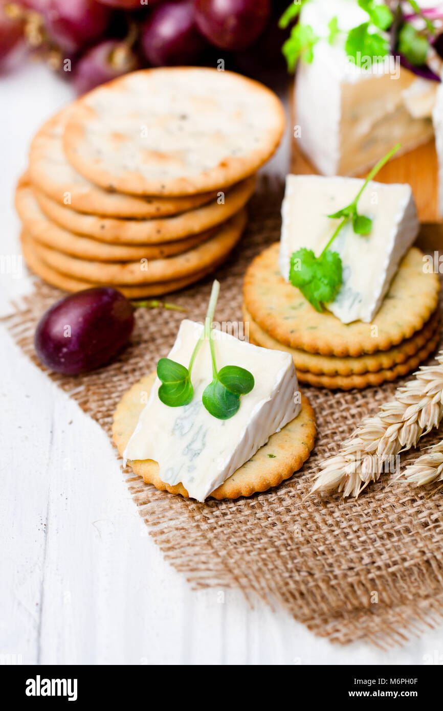 Crackers and wedge of blue camembert cheese on sackcloth napkin Stock