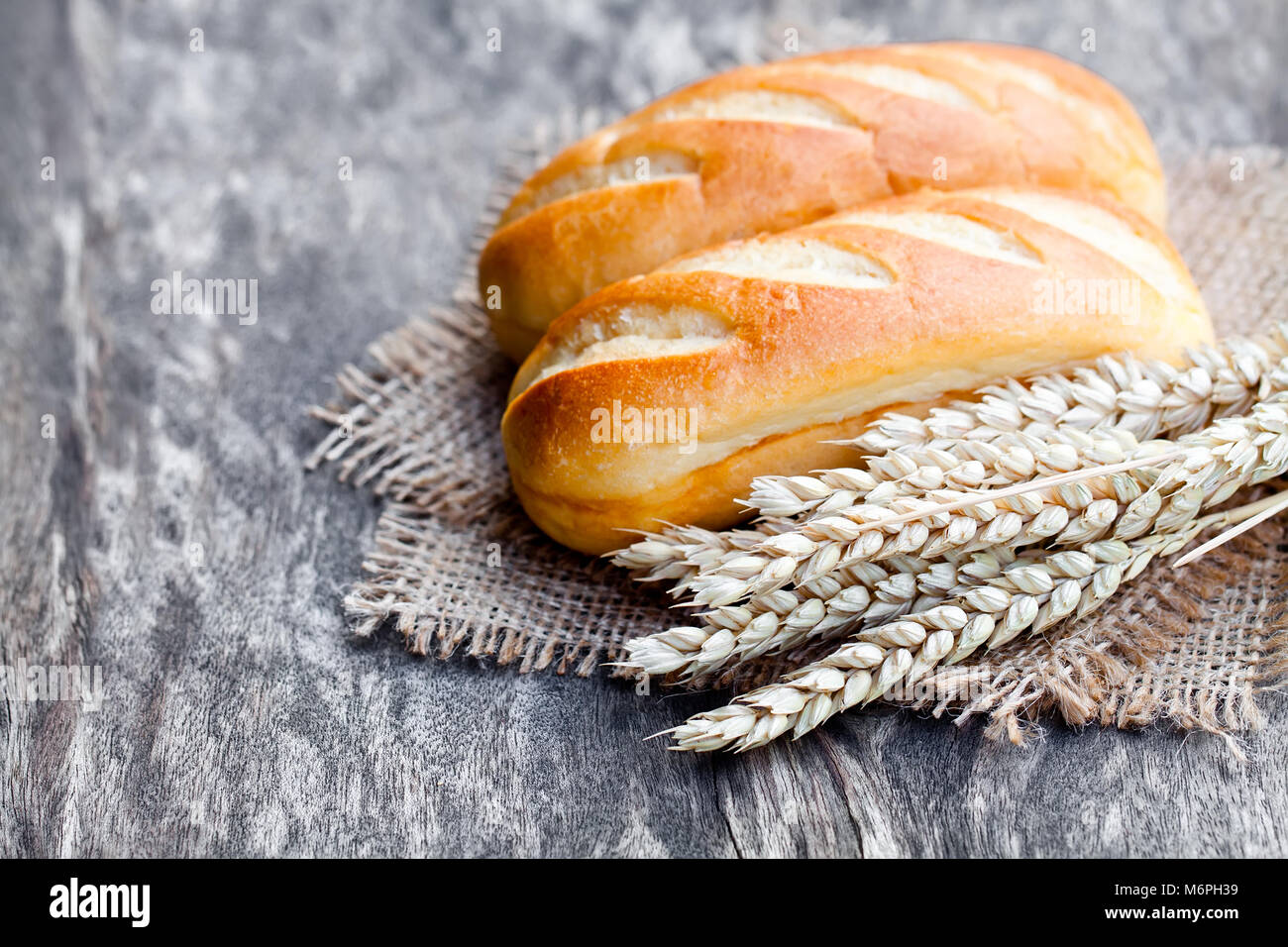 Small  loafs and ears of wheat on sackcloth napkin Stock Photo