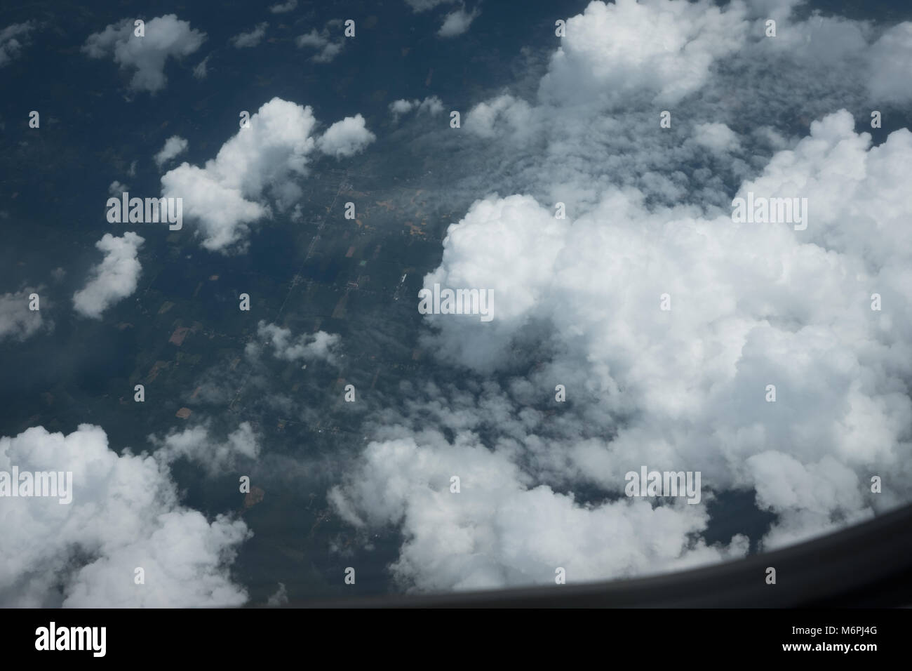 Aerial view above the clouds from airplane window view and dark land background Stock Photo