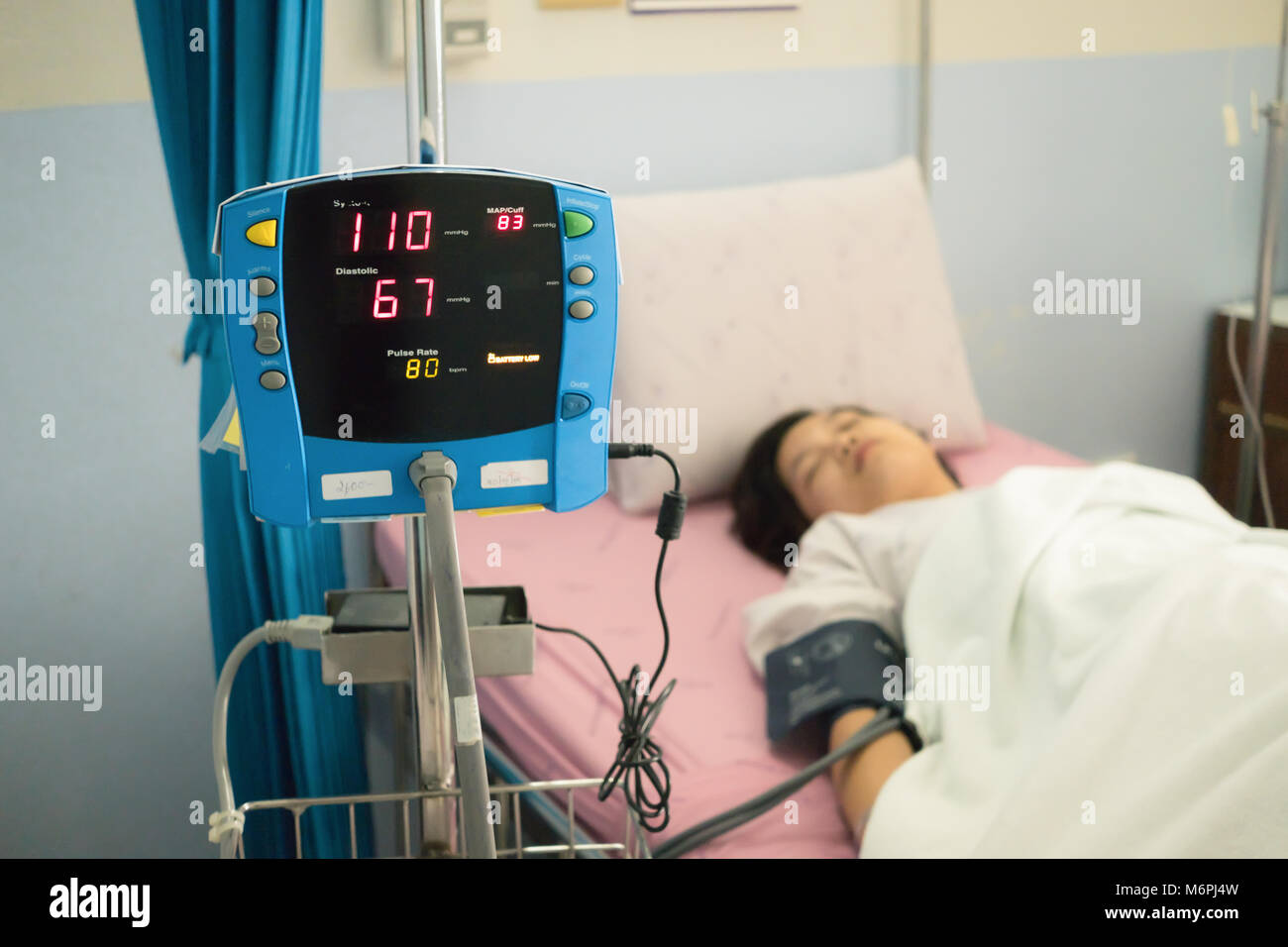 Focus on blood pressure monitor with female patient on bed inside hospital.  Medical concept Stock Photo - Alamy