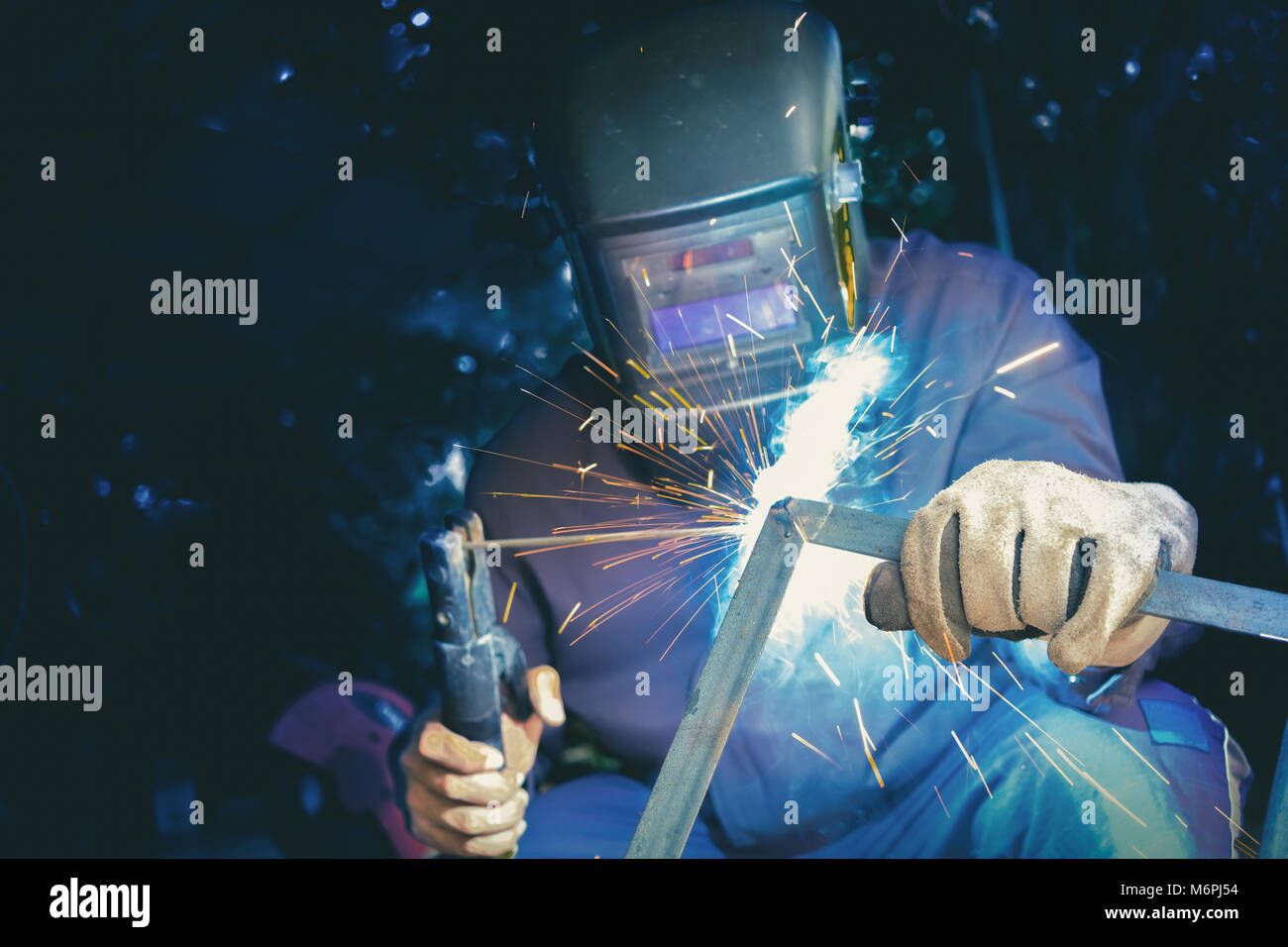 Welder wear protective mask welding metal structure with light sparkle Stock Photo