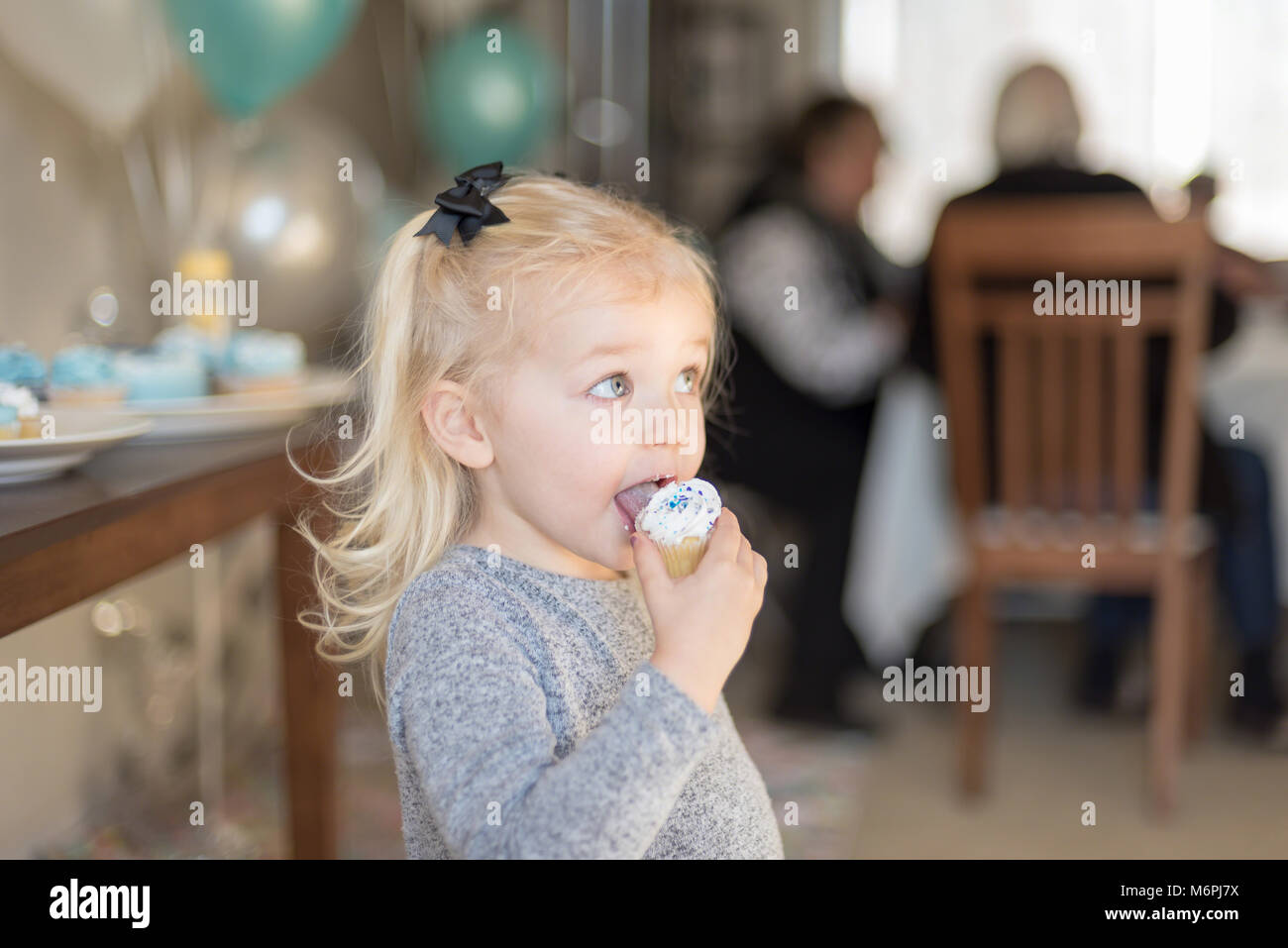 young girl at family birthday party eating a cupcake Stock Photo