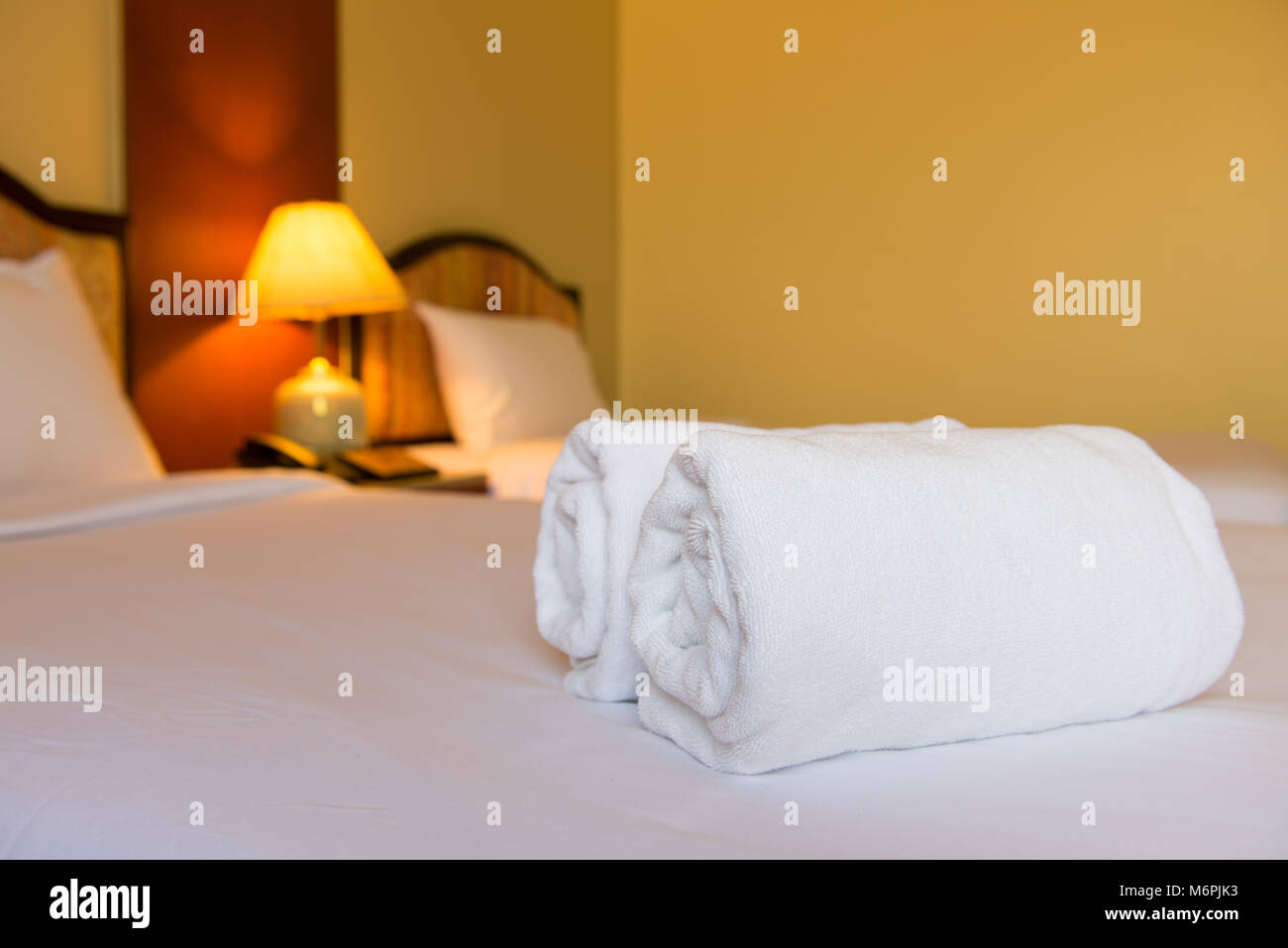Clean towels on white bed Stock Photo