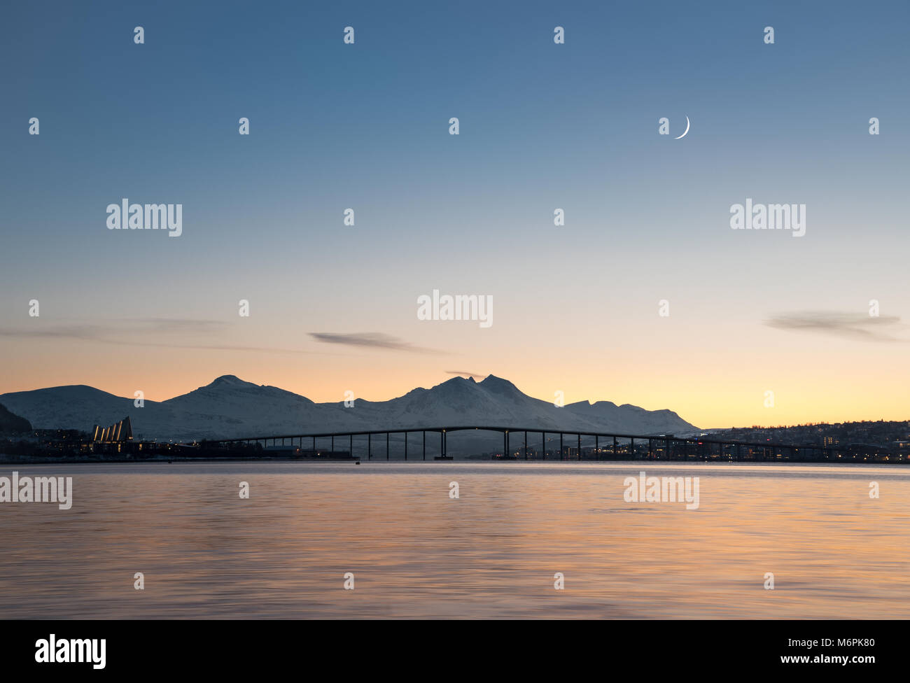 NORWAY, TROMSO - JANUARY 18, 2018: Panoramic view of arctic town Tromso during beautiful dusk with mountains and horned moon background Stock Photo