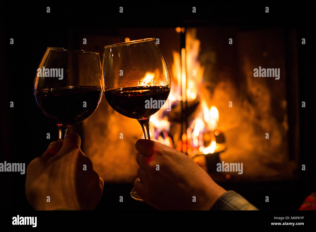 Couple holding pair of glasses with wine at fire pit close up Stock Photo