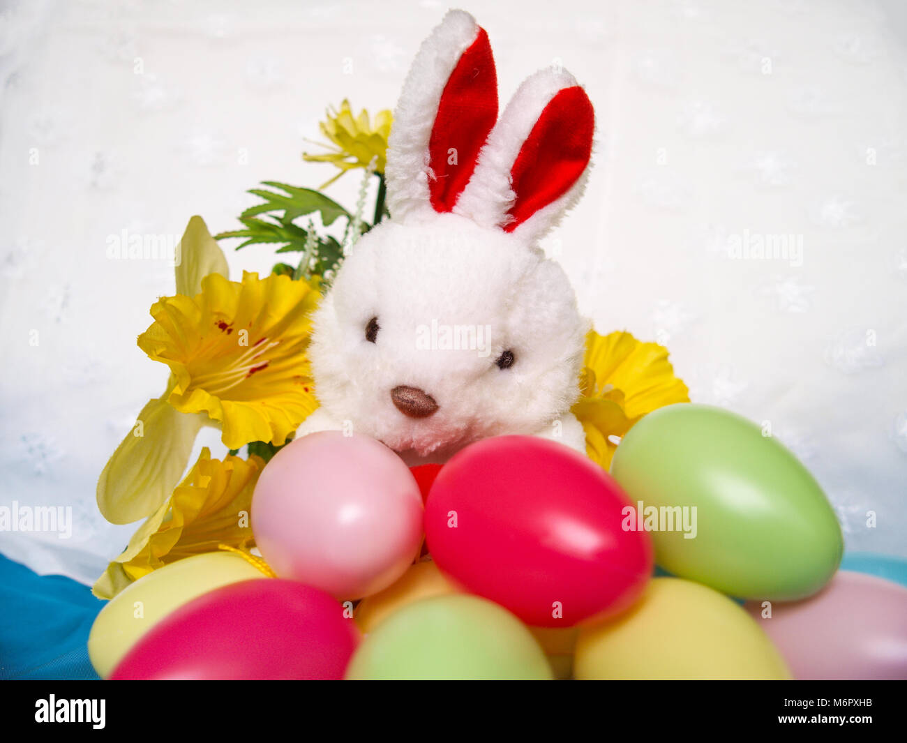 White plush rabbit with colorful Easter eggs and yellow flowers Stock ...