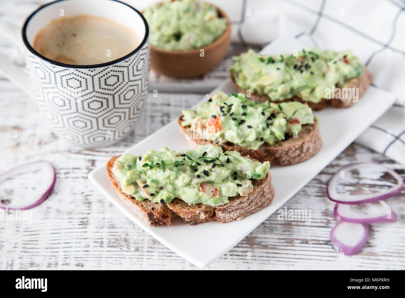 toast with guacamole, seeds and herbs. A cup of coffee. Healyhy Breakfast concept. Stock Photo