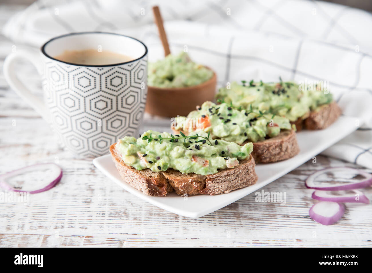 toast with guacamole, seeds and herbs. A cup of coffee. Healyhy Breakfast concept. Stock Photo