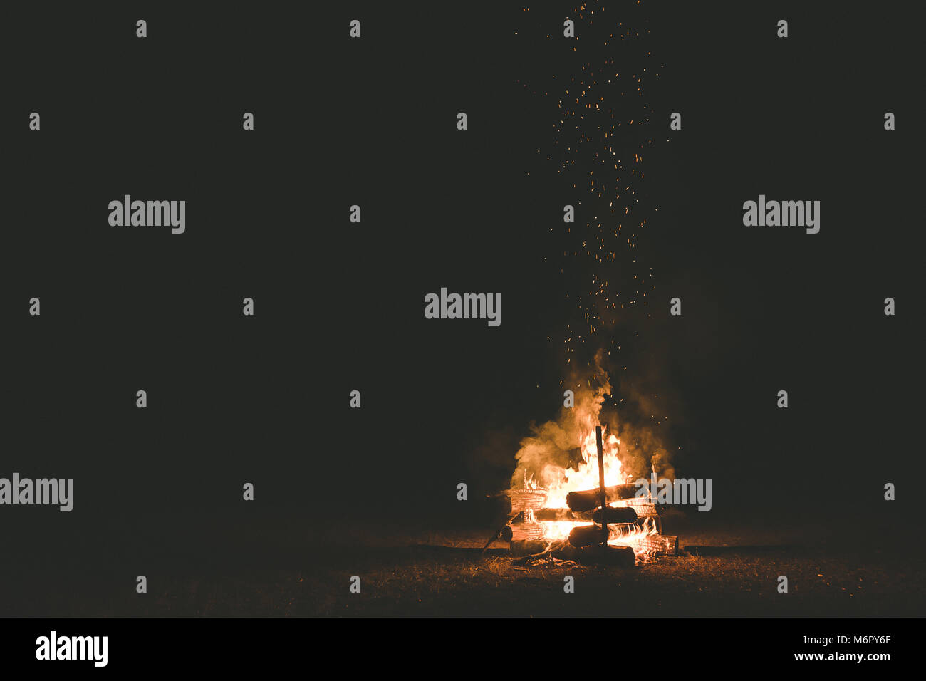 A campfire with sparks flying around in the dark night Stock Photo - Alamy