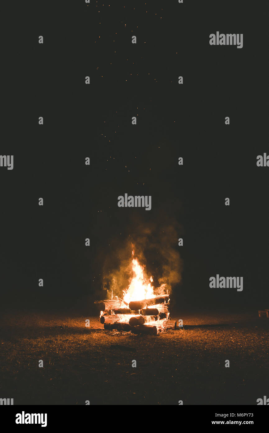A campfire with sparks flying around in the dark night Stock Photo - Alamy