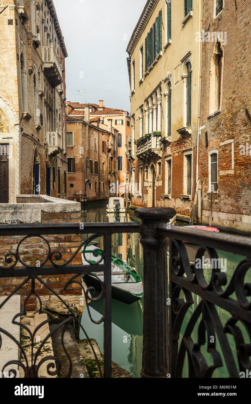 Small romantic canals and narrow aisles with peaks of home during sunset, Venice, Italy Stock Photo