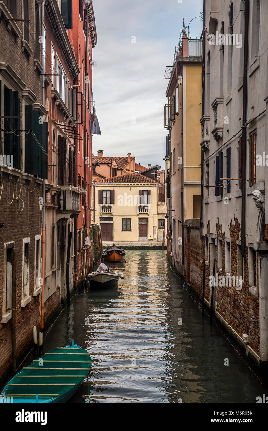 Small romantic canals and narrow aisles with peaks of home during sunset, Venice, Italy Stock Photo