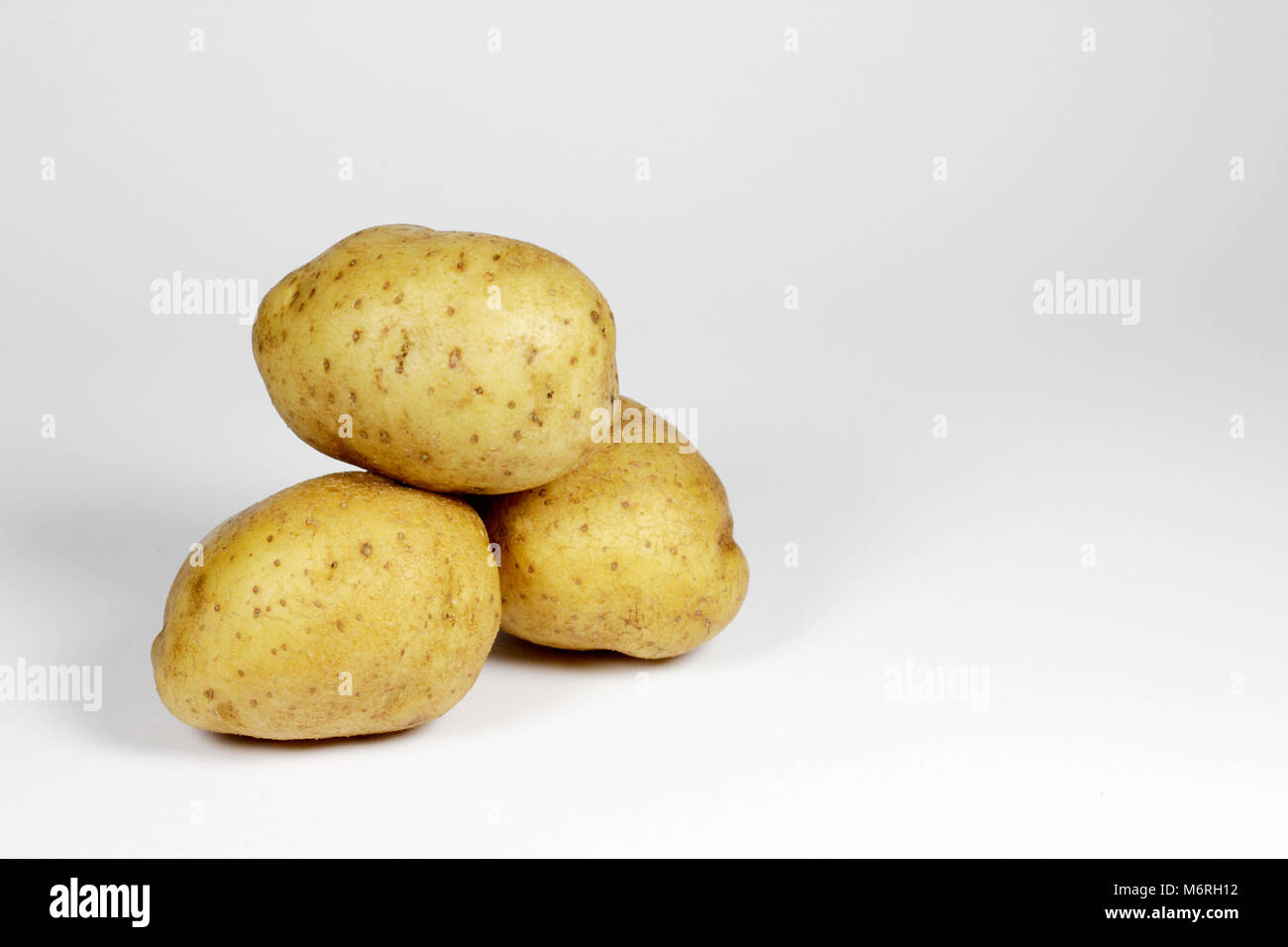 Three potatoes with a white background arranged piled up Stock Photo