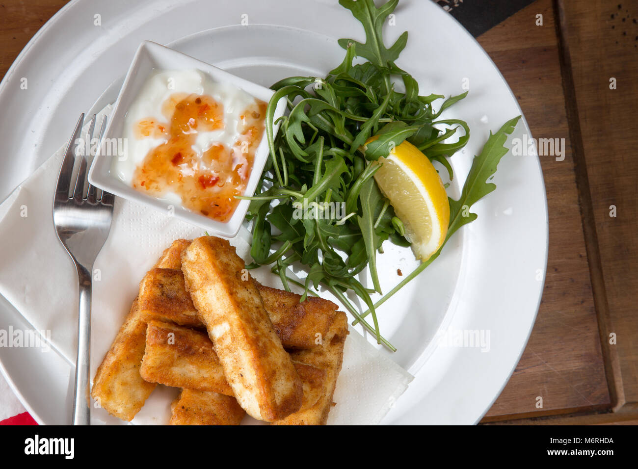 A starter course of Halloumi cheese fries with a Rocket salad and yogurt with sweet chili sauce dip taken in an English pub restaurant Stock Photo