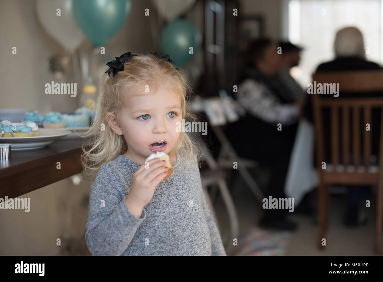 young girl at family birthday party eating a cupcake Stock Photo