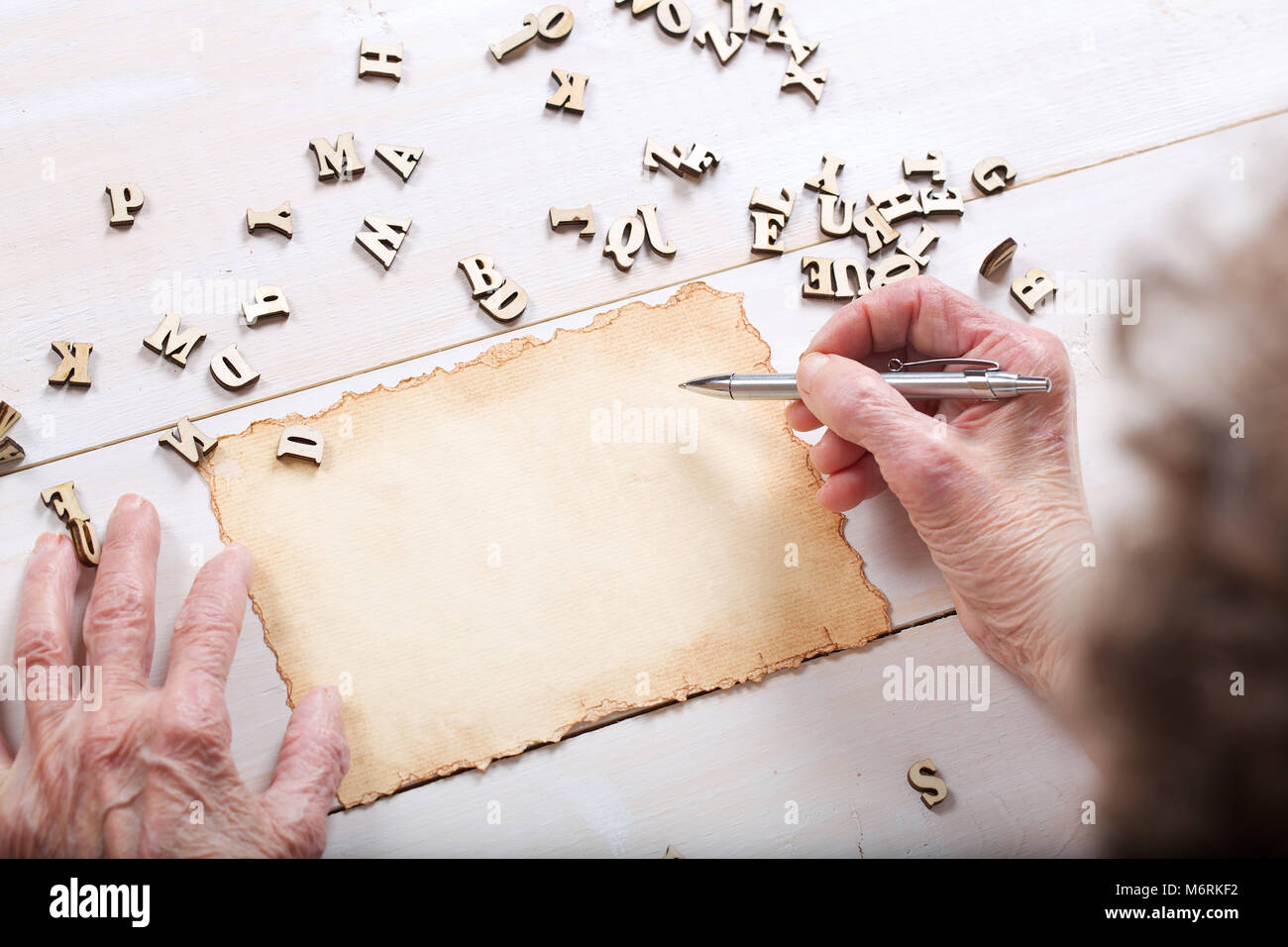 Senior woman wants to write something on a piece of paper. Wooden ...