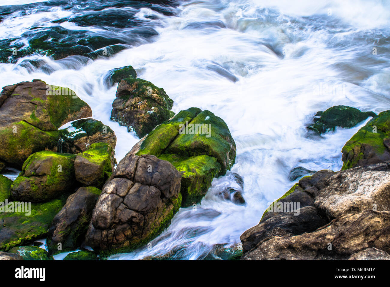 Beach with green textured rocks Stock Photo - Alamy