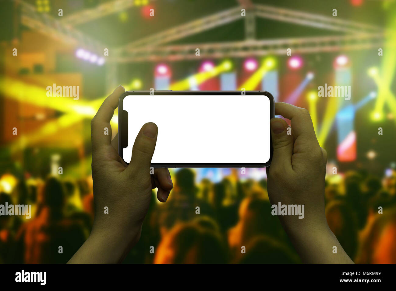Modern smart phone in woman hand. Live music concert in background. Stock Photo