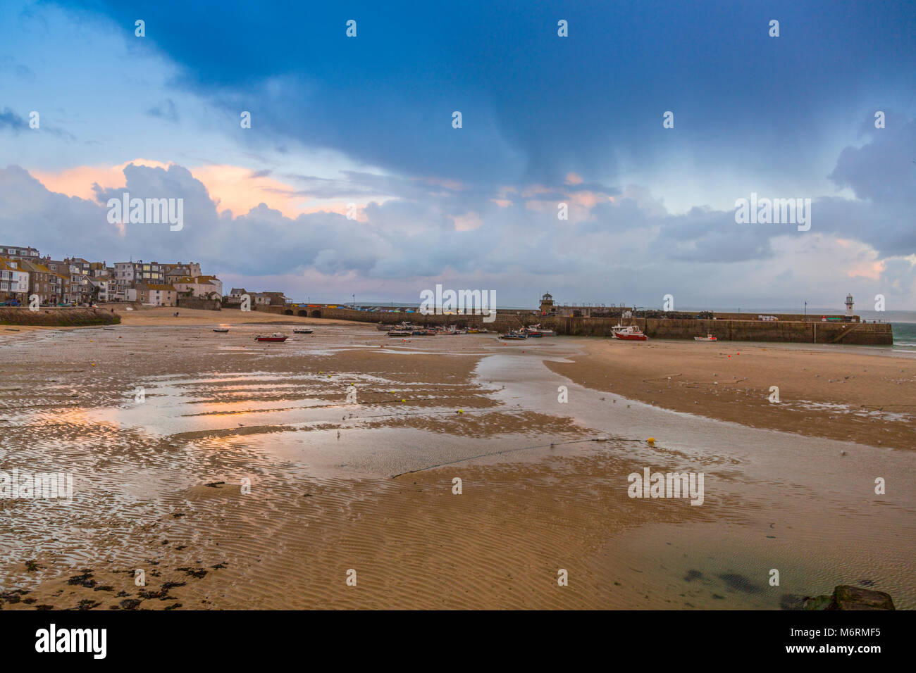 A low tide and stormy skies above a deserted harbour in winter in St Ives, Cornwall, England, UK Stock Photo