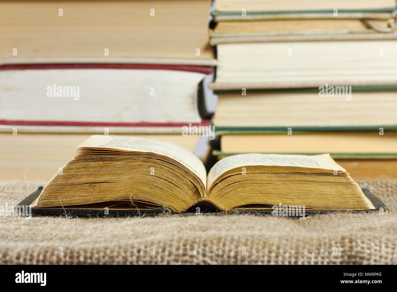 Open old book in a hard cover on a table with a jute background Stock Photo