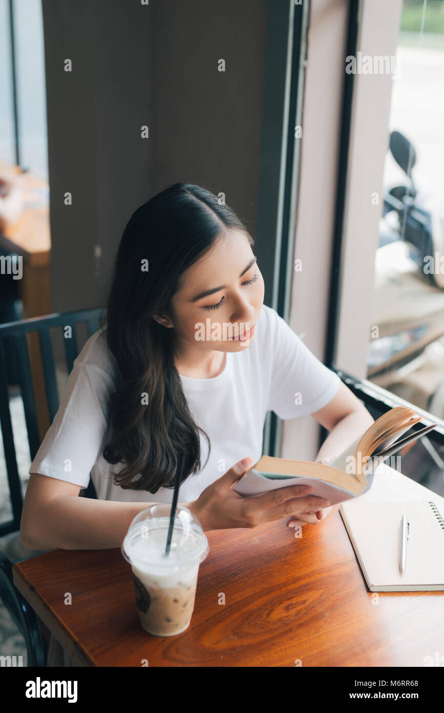 Portrait of Asian woman reading book in coffee shop cafe vintage color tone Stock Photo