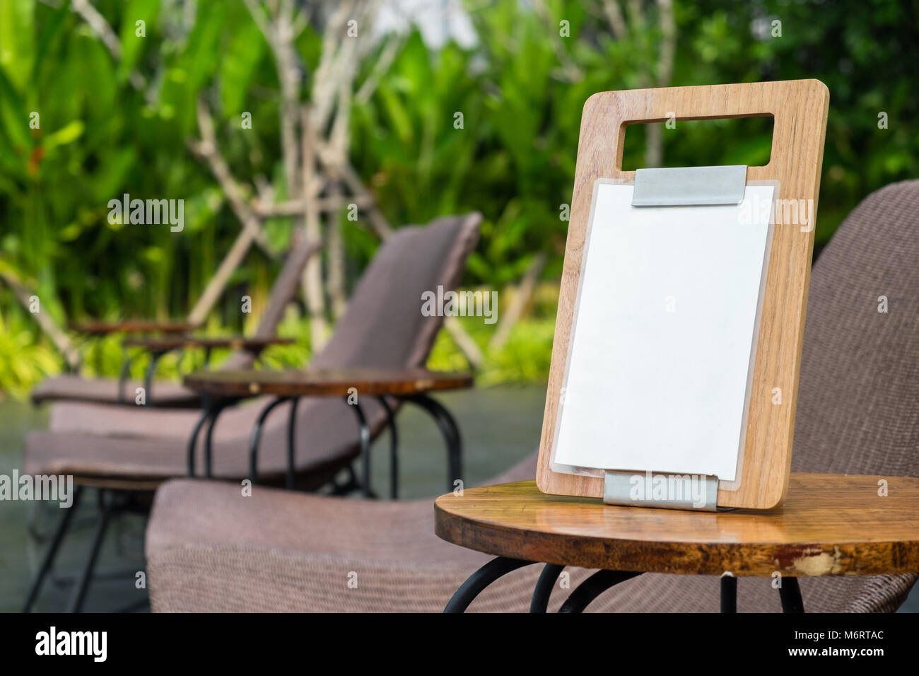 Empty menu frame standing on wood table in outdoor coffee shop near the garden, Copy space for text Stock Photo