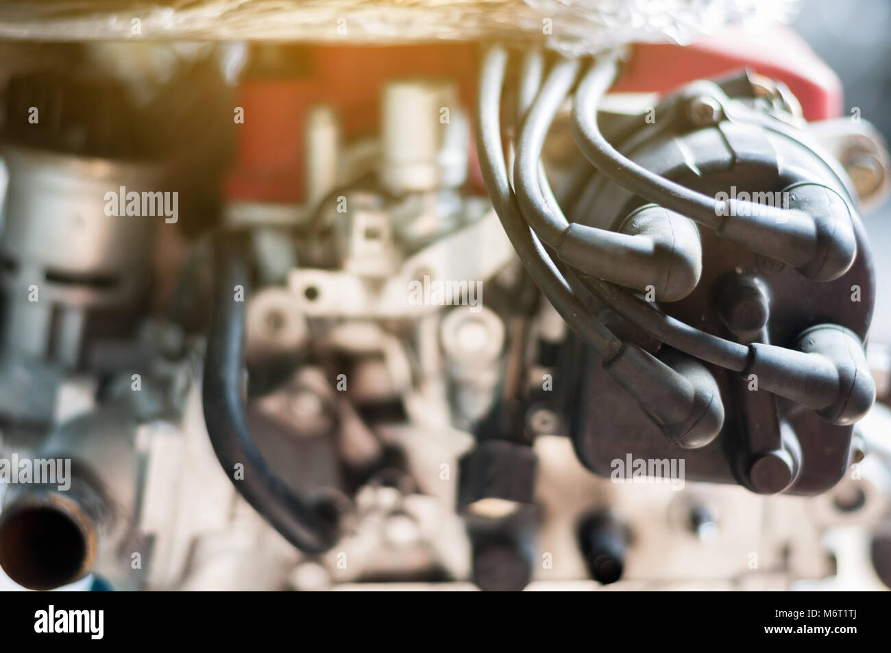 Close up coil distributor wire four cylinder engine stand on car with sunlight - Stock Image