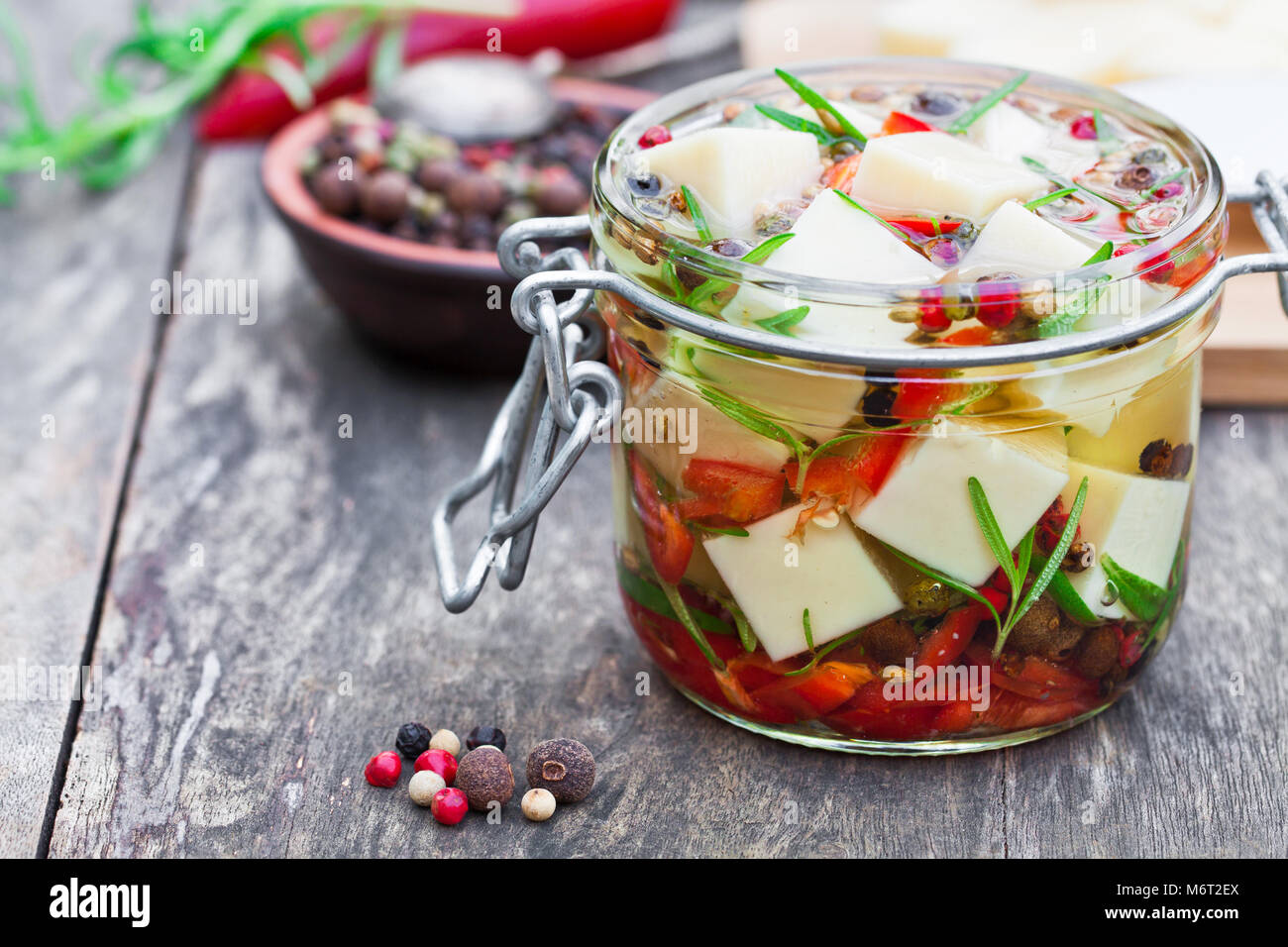 white cheese cubes and herbs dipped in olive oil in small jar on wooden