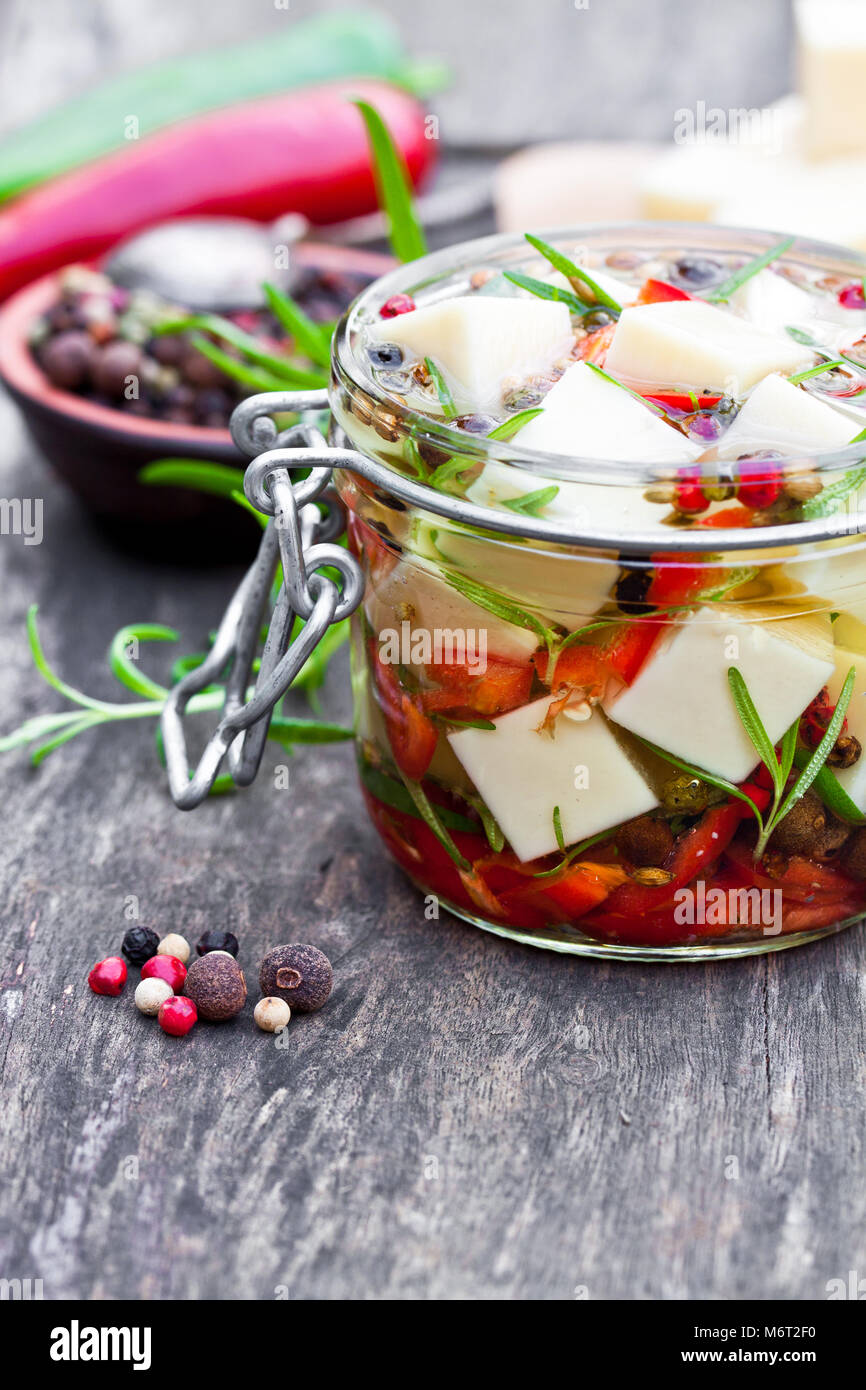 white cheese cubes and herbs dipped in olive oil in small jar on wooden