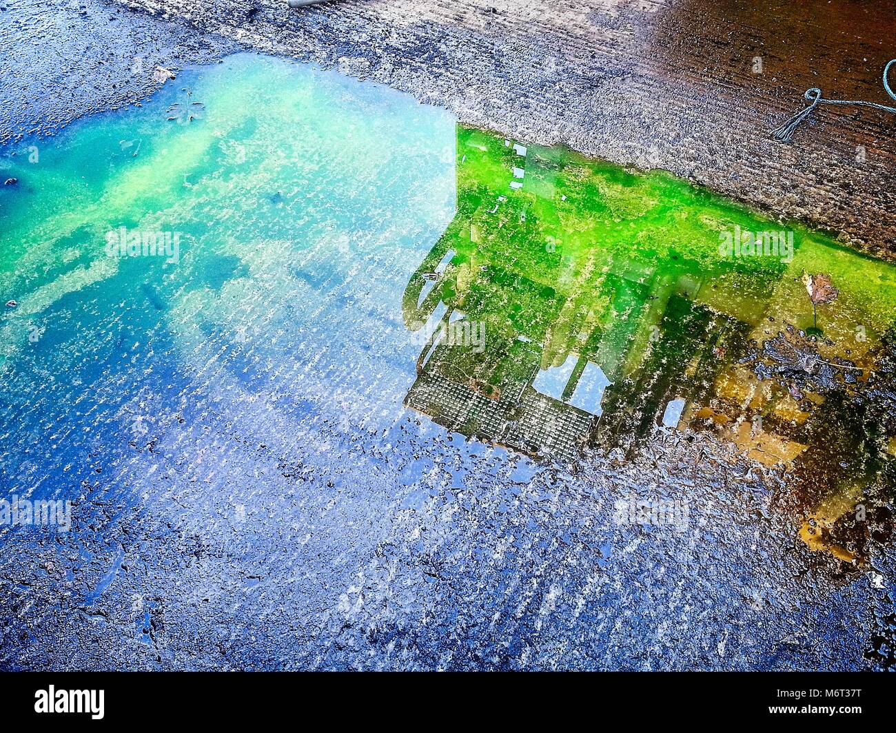 Oil and gas equipment reflected in the puddle. Very bright colors Stock Photo