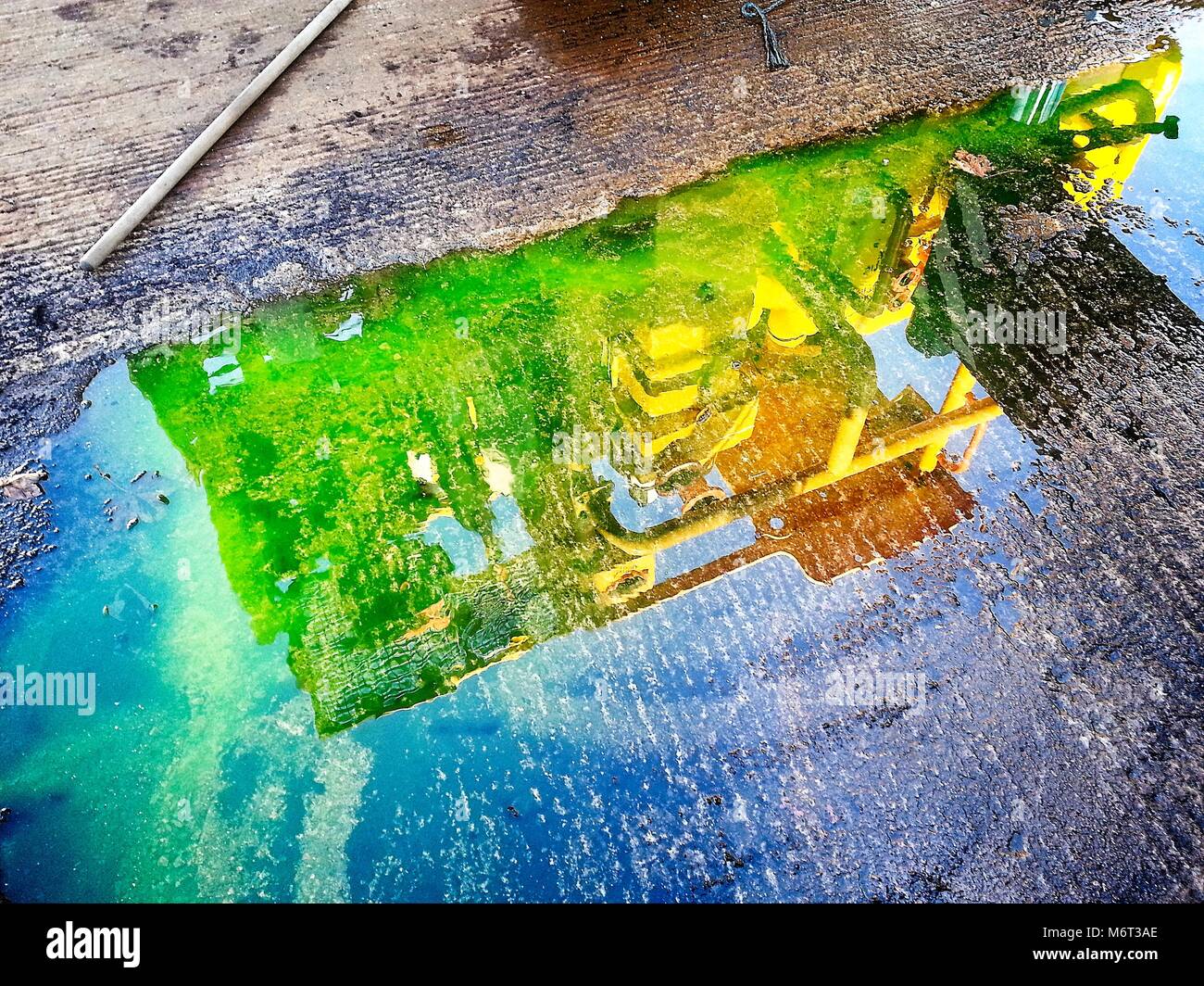 Oil and gas equipment reflected in the puddle. Very bright colors Stock Photo