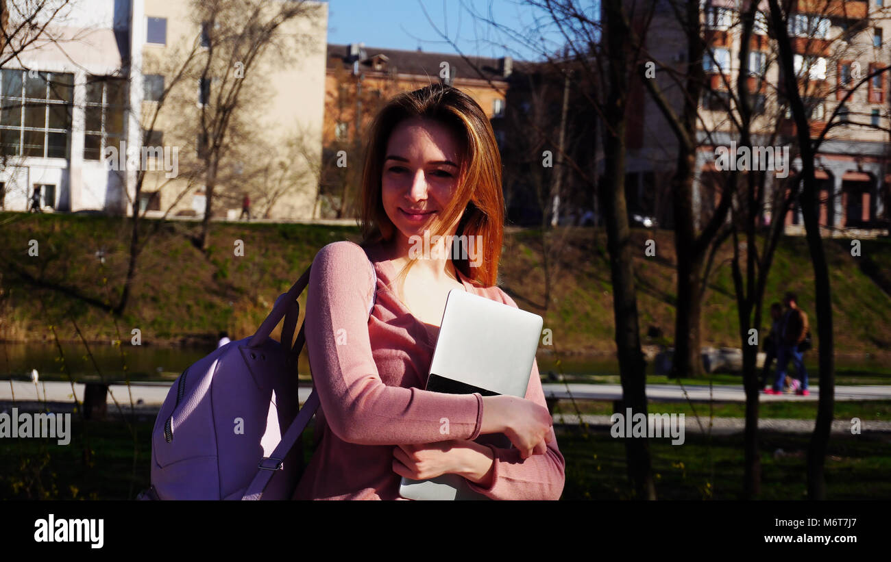 Happy student walking in park with laptop and backpack Stock Photo - Alamy