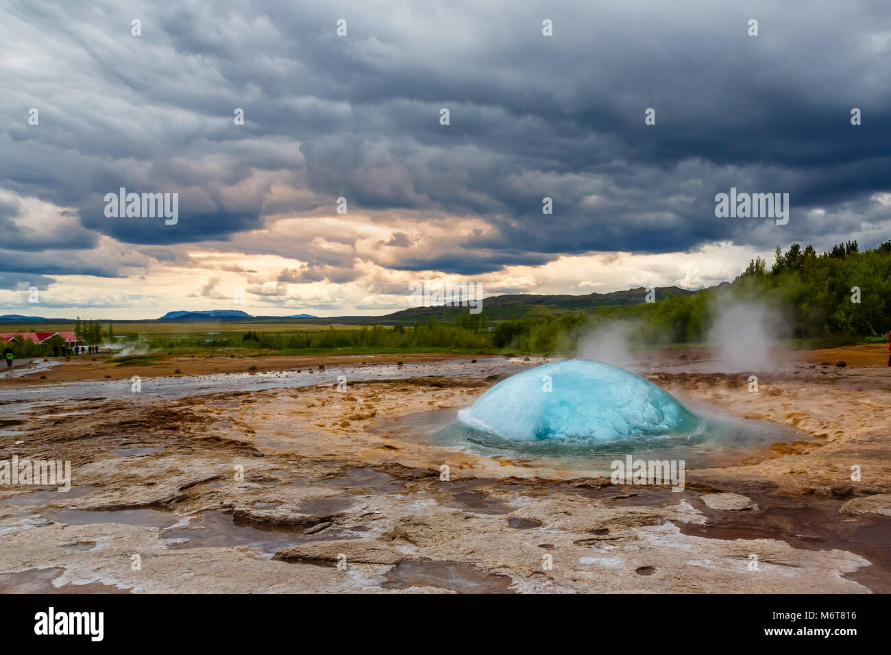 Famous Strokkur fountain geyser hot blue water explosion with cloud sky and surrounding Icelandic landscape, Iceland Stock Photo