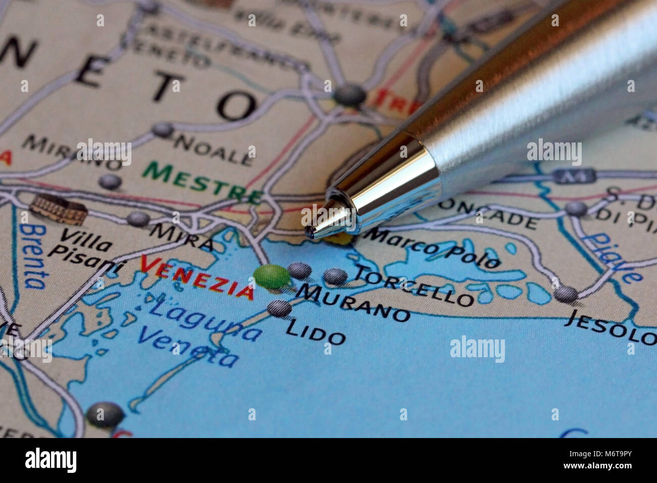 Macro image of a ballpoint pen pointing at Venice on the map of Italy. Shallow depth of field. Stock Photo