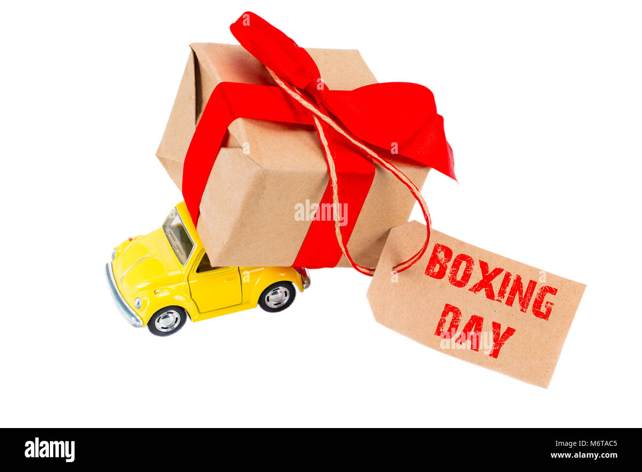 The BOXING DAY concept. Yellow retro toy car delivering gifts box with tag with text BOXING DAY on white background. Stock Photo