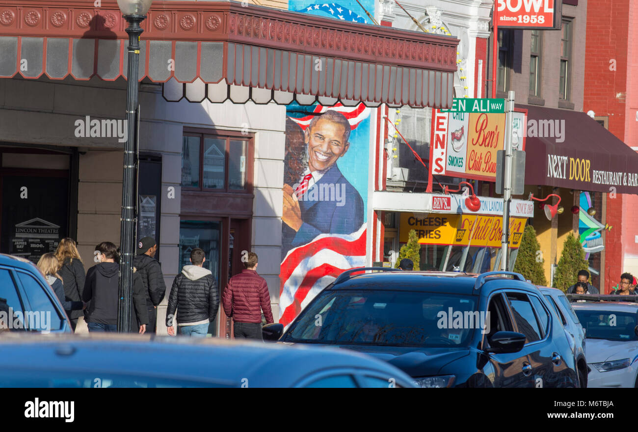 Pedestrians walk by a wall mural featuring Barack Obama, on Ben's Chili